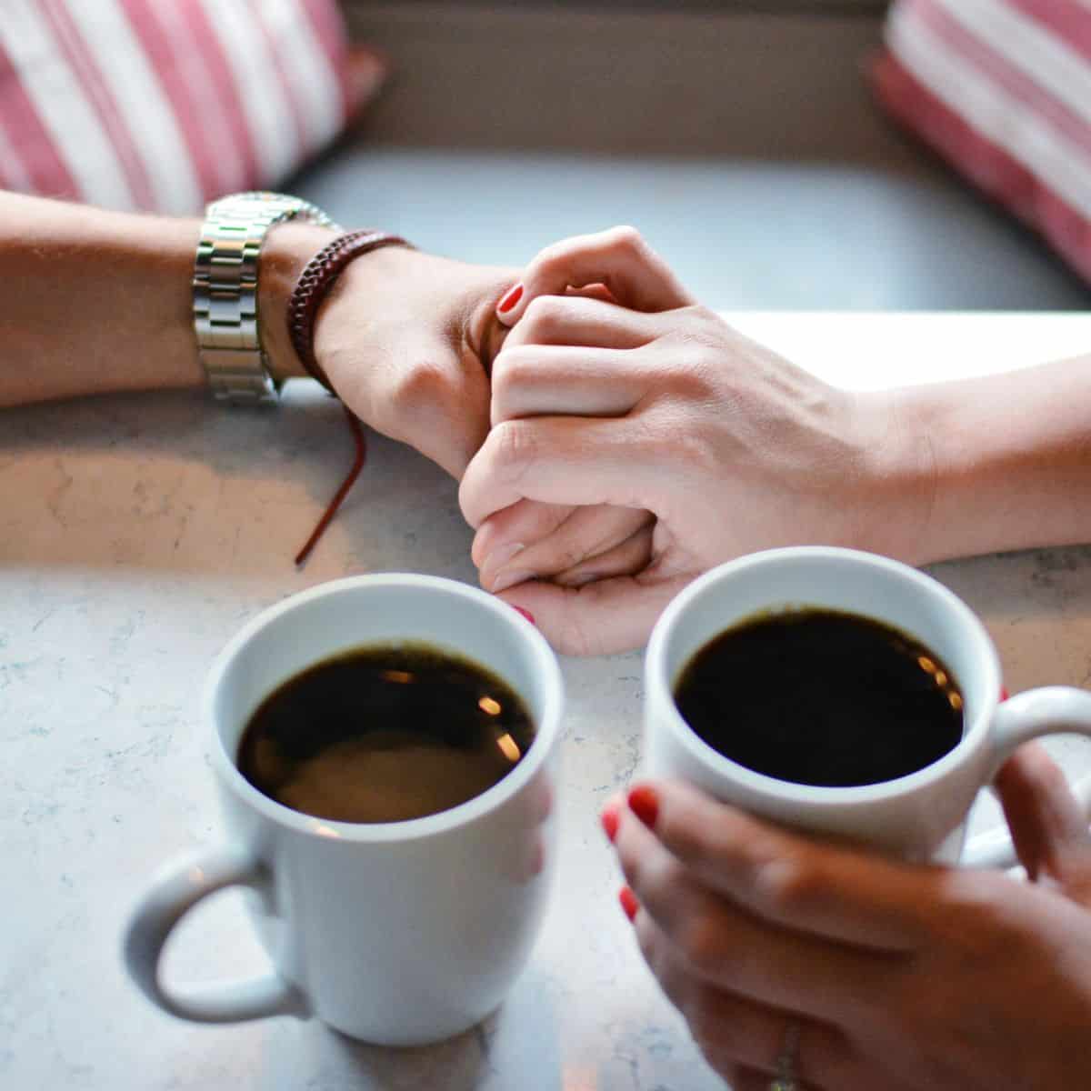 two hands holding, with cups of coffee